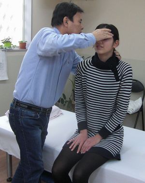 座っている女性に施術している中橋院長の写真